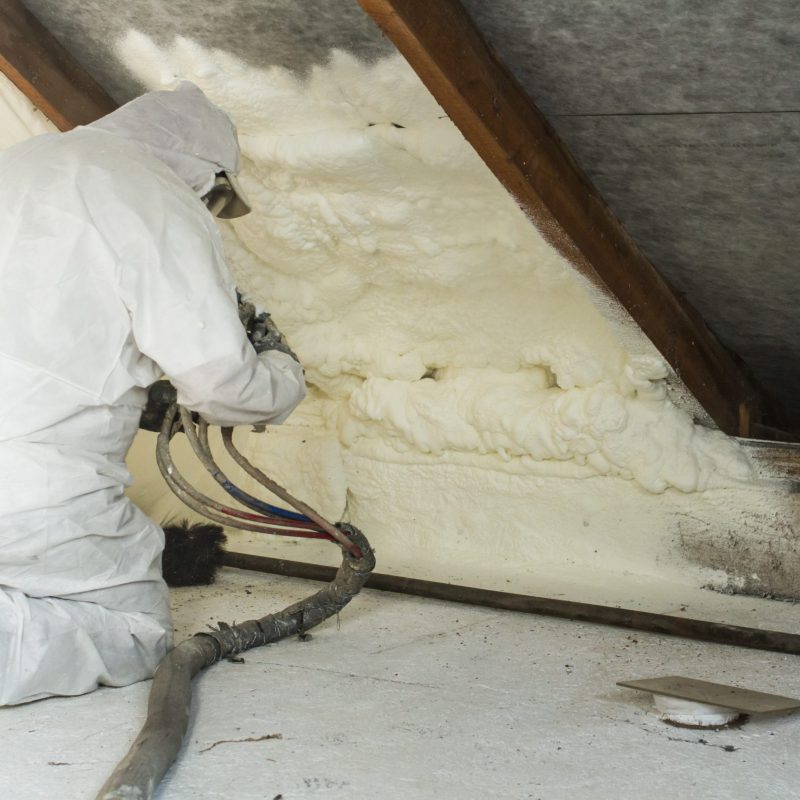 spray polyurethane foam for roof - technician spraying foam insulation using plural component gun for polyurethane foam, inside